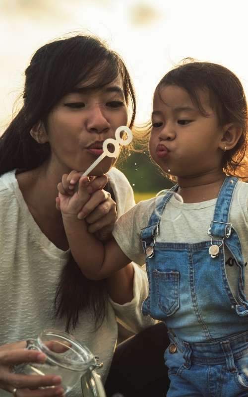 Mother and daughter outside blowing bubbles500x800